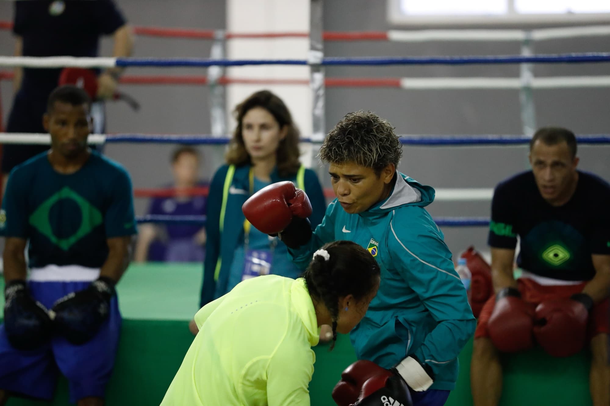 Boxeadora de luvas vermelhas treina golpes com a técnica no ringue