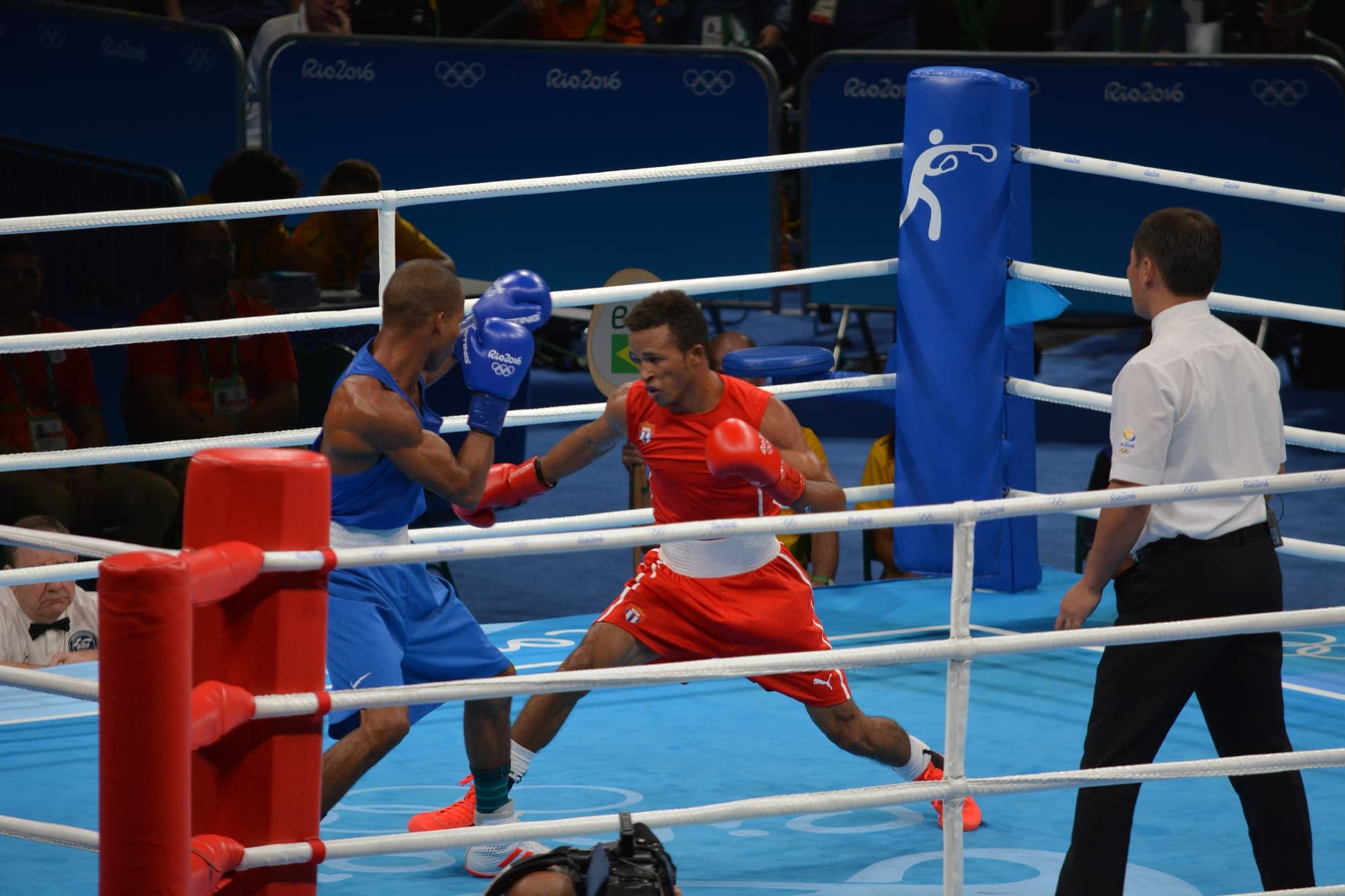 Dois boxeadores trocam golpes no ringue, o brasileiro de azul