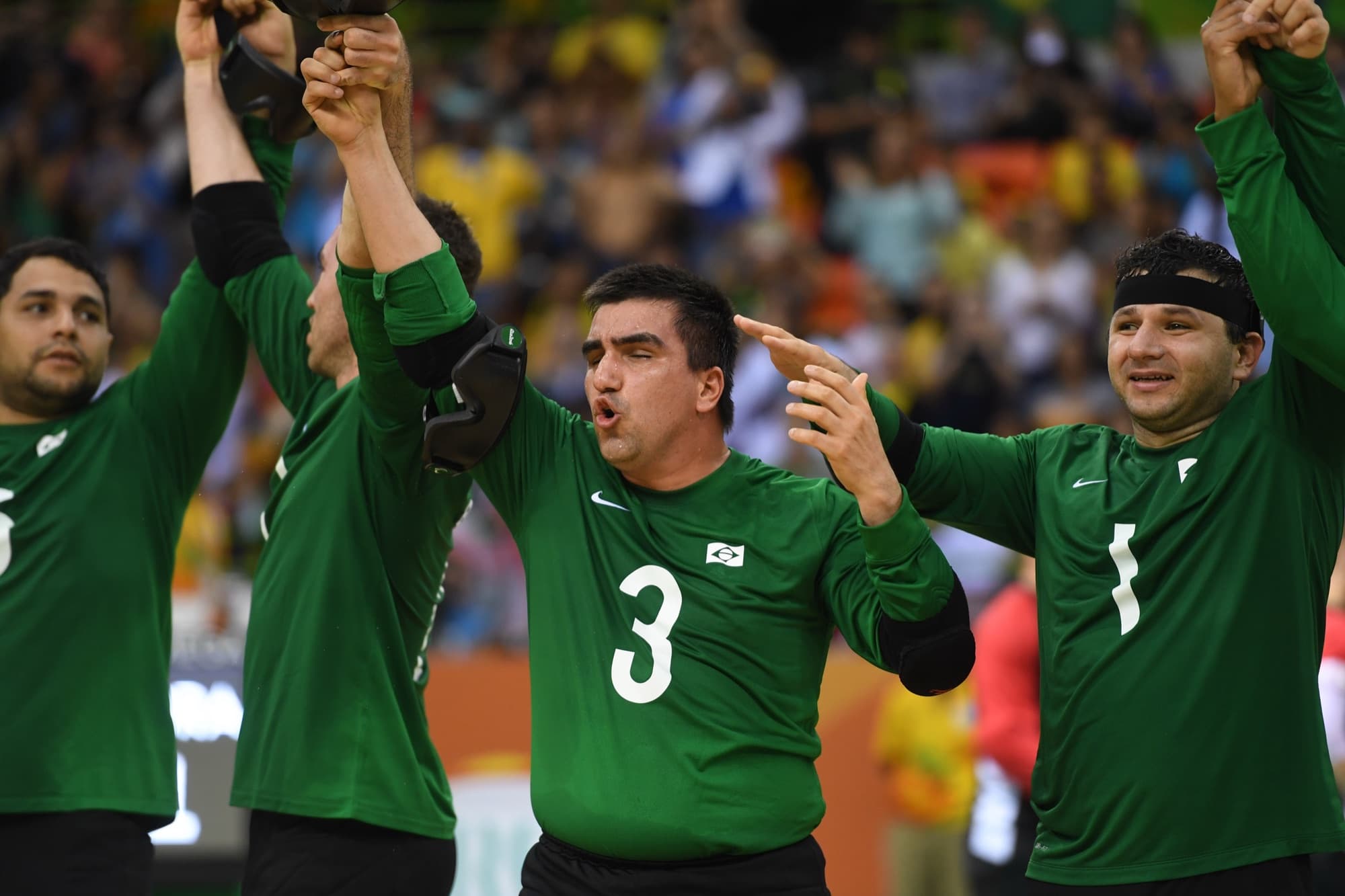 Jogadores de goalball comemoram juntos, de braços erguidos, depois da partida