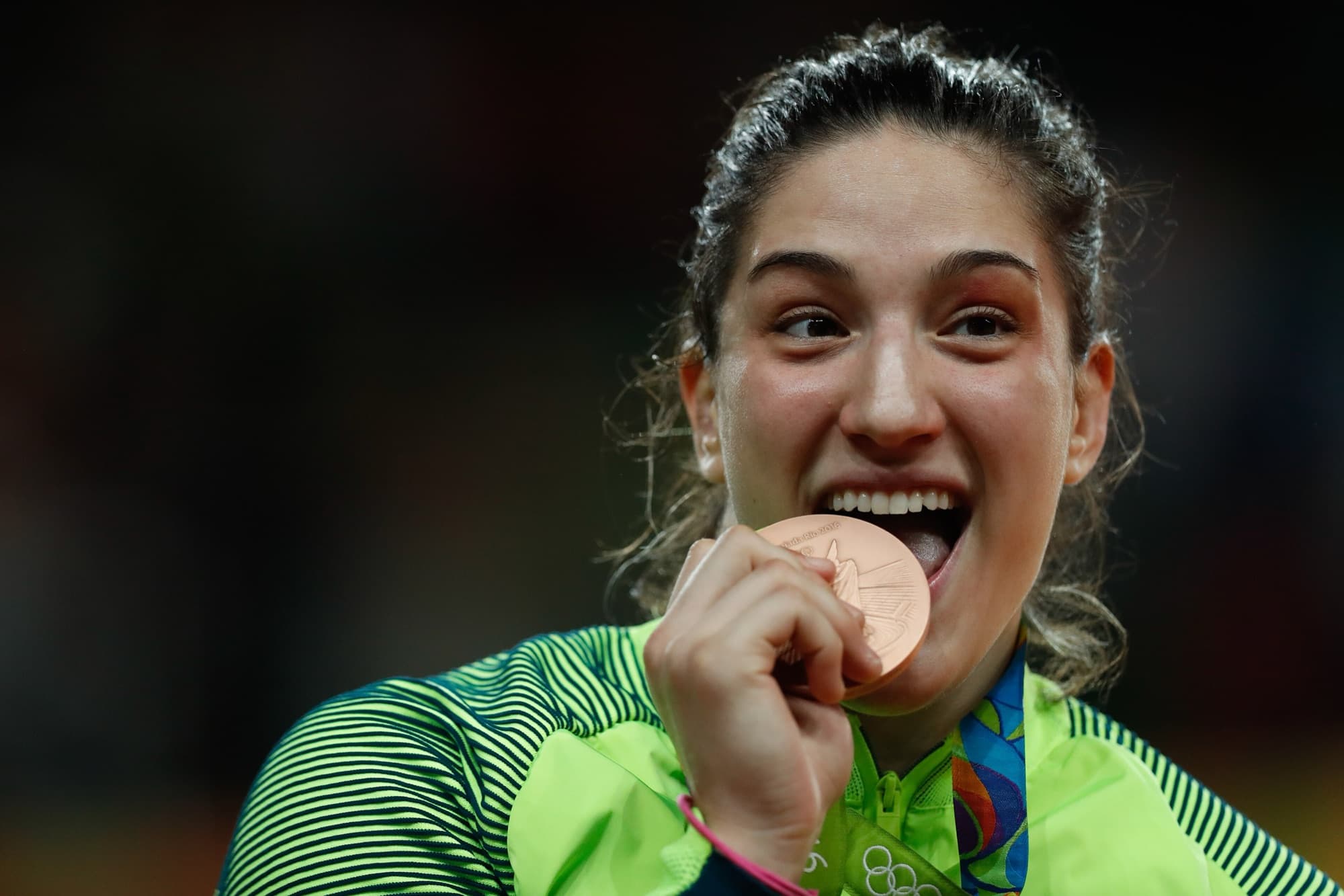 Judoca sorri e morde a medalha no pódio
